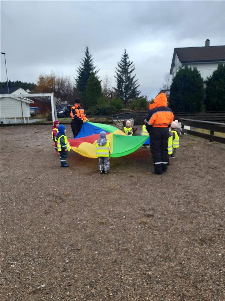 Barn og vaksne leker med fallskjerm ute - Klikk for stort bilete