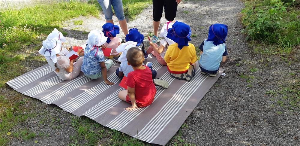 Barn som sitter på eit teppe ute - Klikk for stort bilete